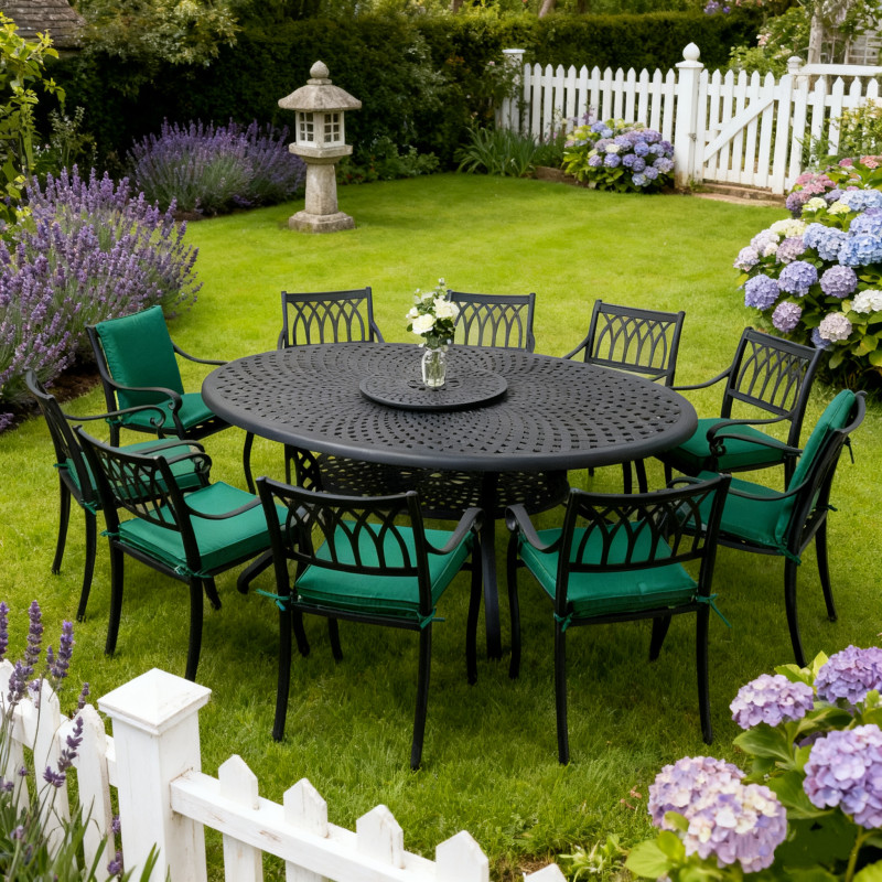A circular outdoor dining table with eight chairs, each set with a white plate, surrounded by a green lawn and brick house.