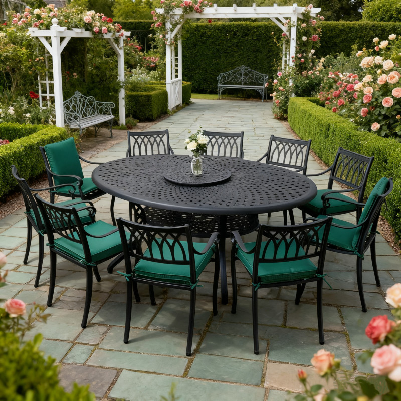 Round black metal dining table surrounded by ten chairs with cushions, set on green grass in a garden.