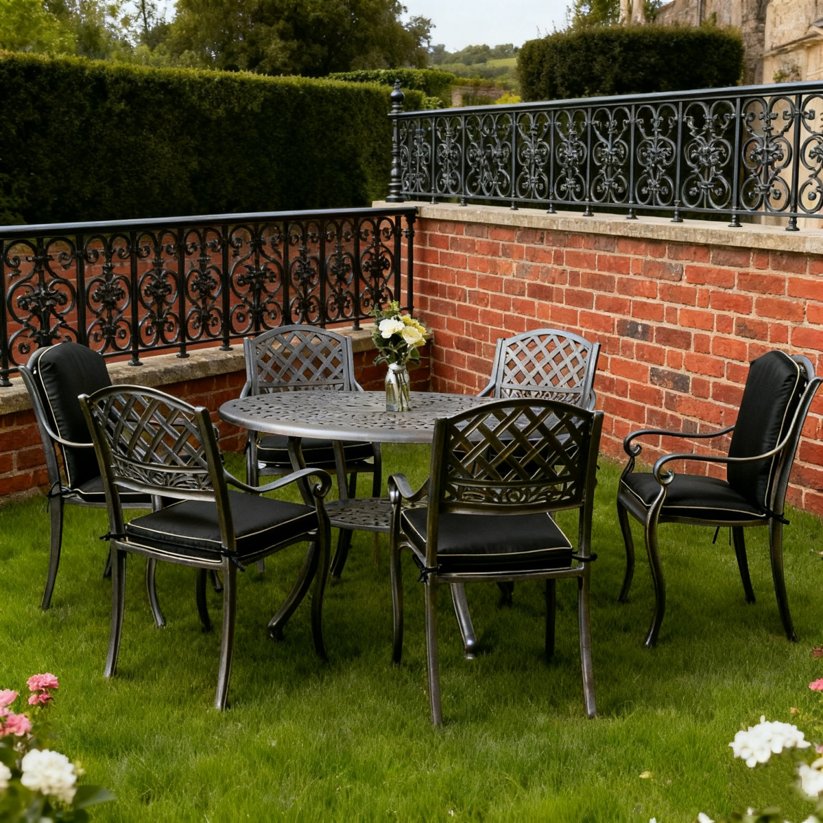 Garden setting featuring a round black table with a centre umbrella and bright green chairs amidst blooming flowers and shrubs.