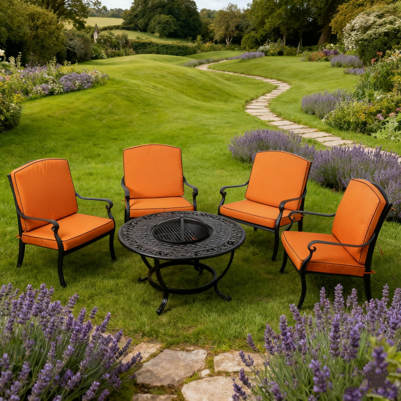Four cushioned garden chairs surround a circular metal table on gravel, with a green landscape and trees in the background.