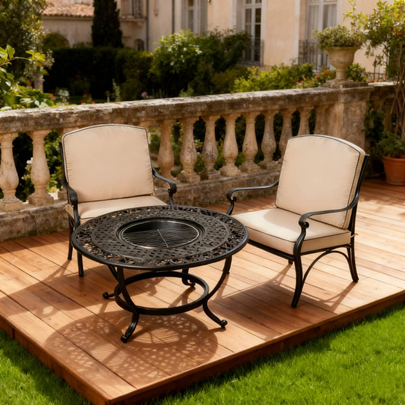 Black cushioned garden sofa beside a round metal table, set on gravel with green grass and plants in the background.