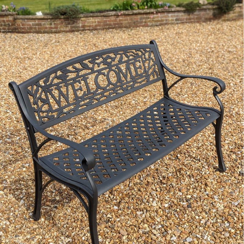 A circular outdoor dining table with eight chairs, each set with a white plate, surrounded by a green lawn and brick house.