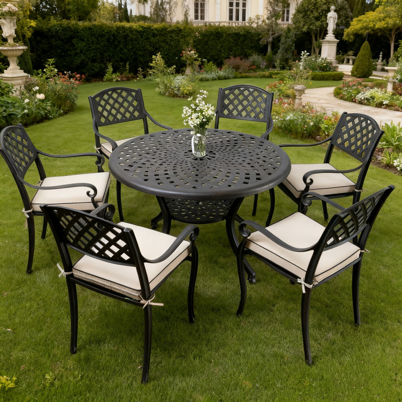 A garden table with six chairs under a black parasol, featuring a bowl of fruit and a white jug, surrounded by greenery.