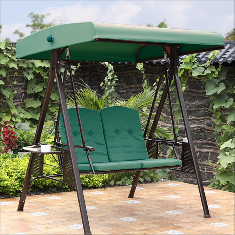 A green garden swing bench with a canopy and two cushioned seats, including a round lumbar pillow.